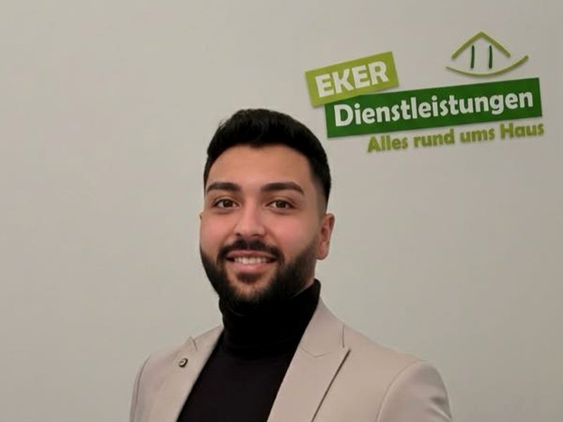Özgür Eker vor dem Logo von Eker-Dienstleistungen